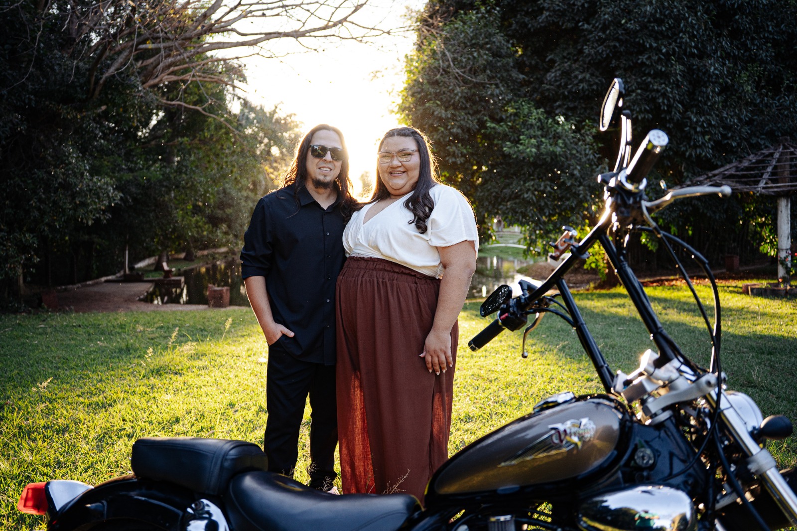 Evelyn e Felipi com motocicleta ao pôr do sol
